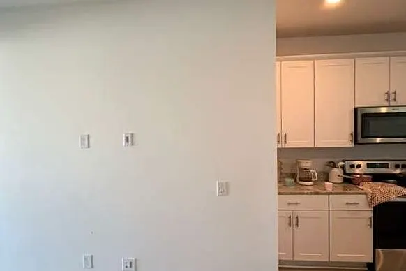 Bare living room wall with a kitchen visible to the right before cabinetry was installed
