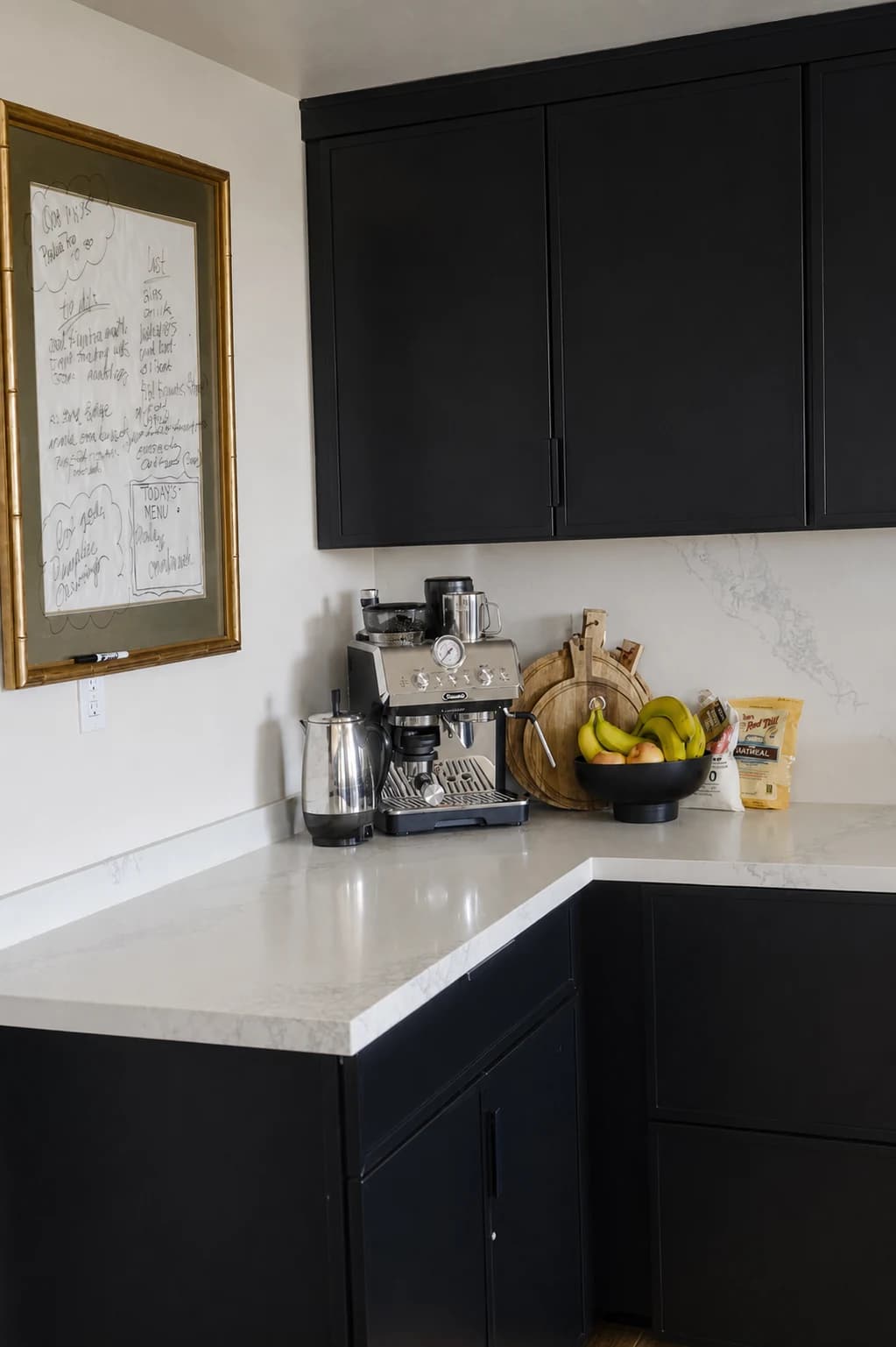 Kitchen coffee station with black cabinetry, white stone counters, and small appliances