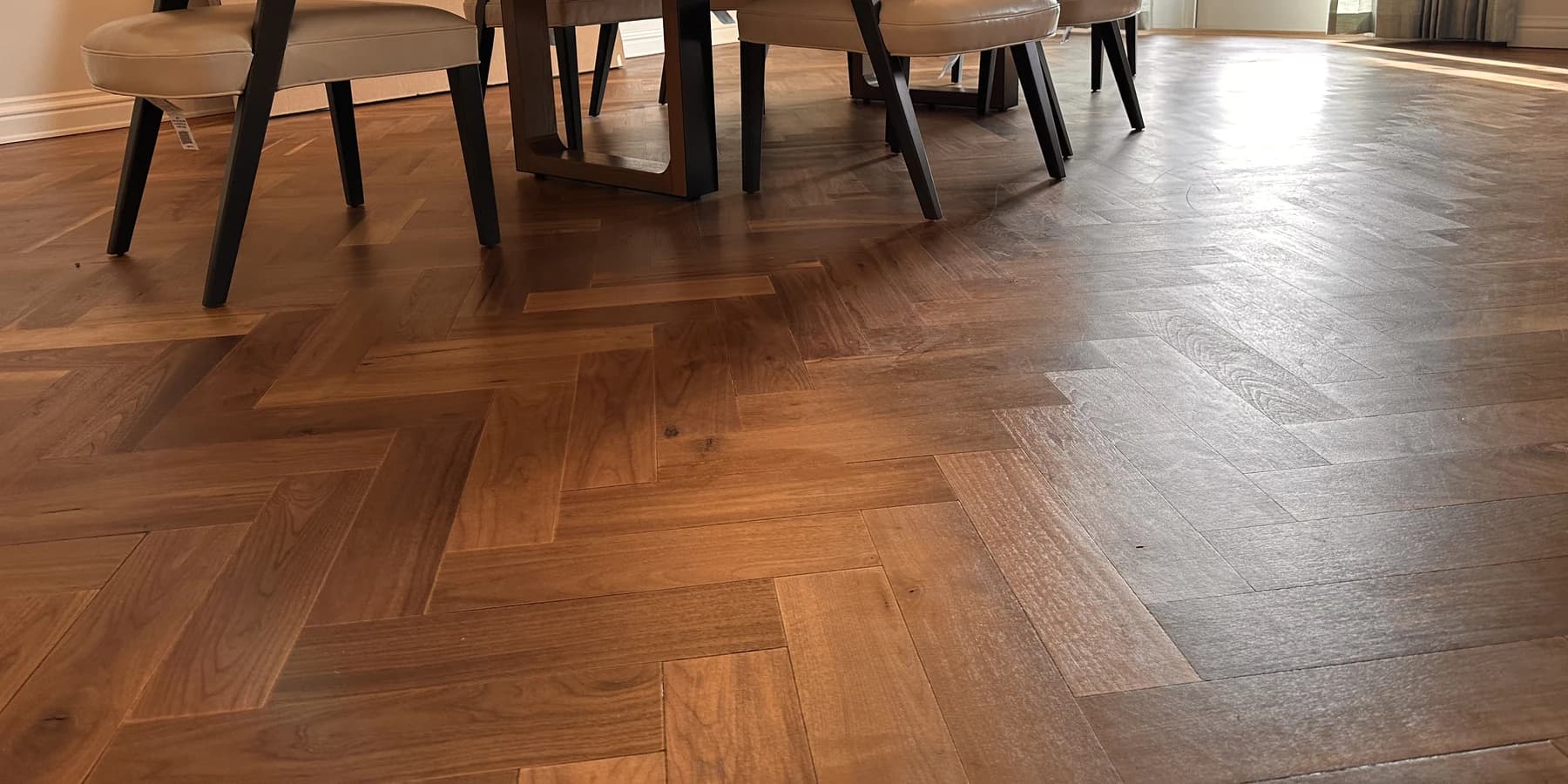 Brown herringbone wood flooring beneath dining furniture in a completed Carlsbad flooring project