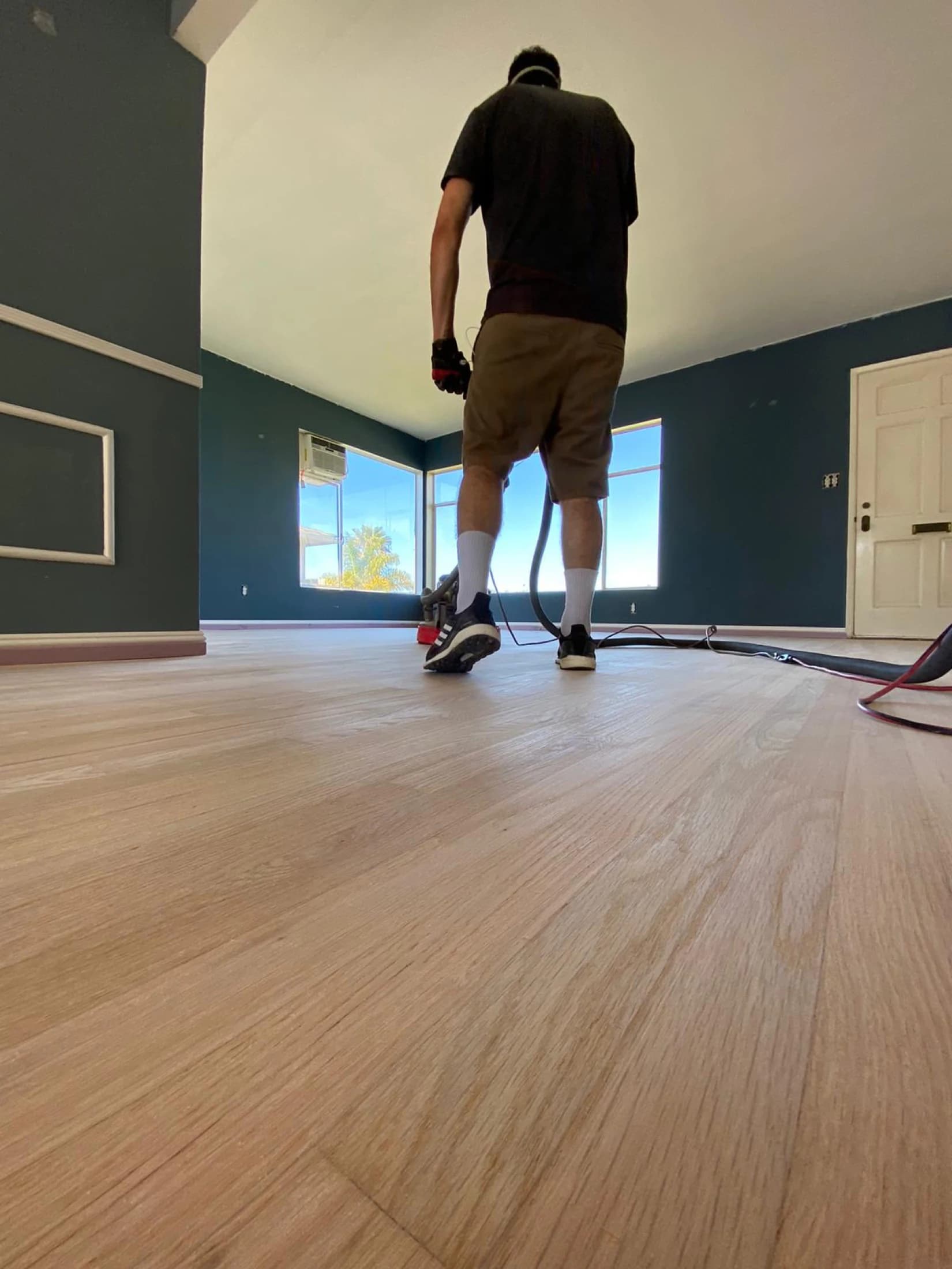 Flooring specialist sanding a hardwood floor with dust-containment equipment