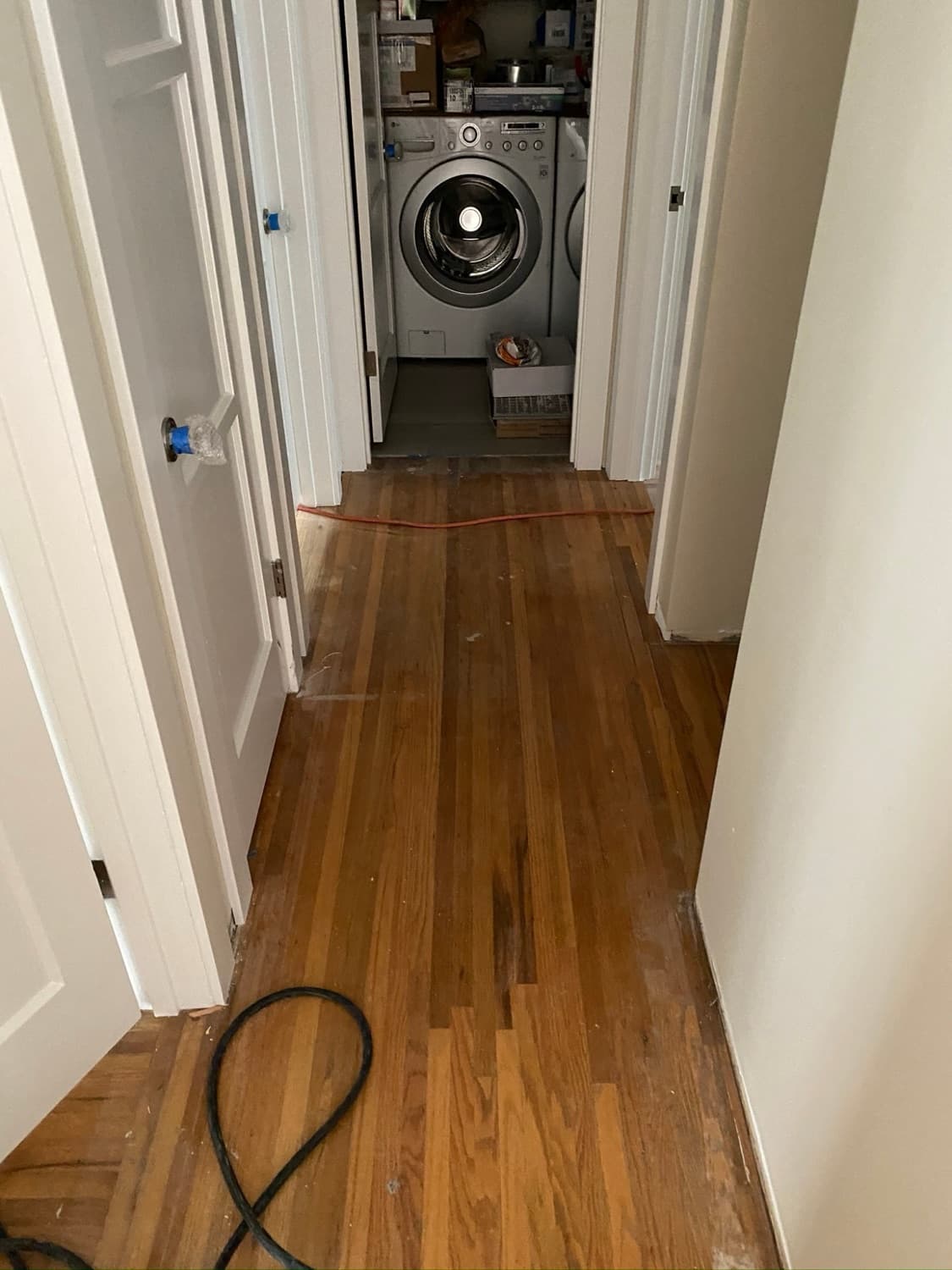Worn hallway hardwood floor with dull patches and scratches