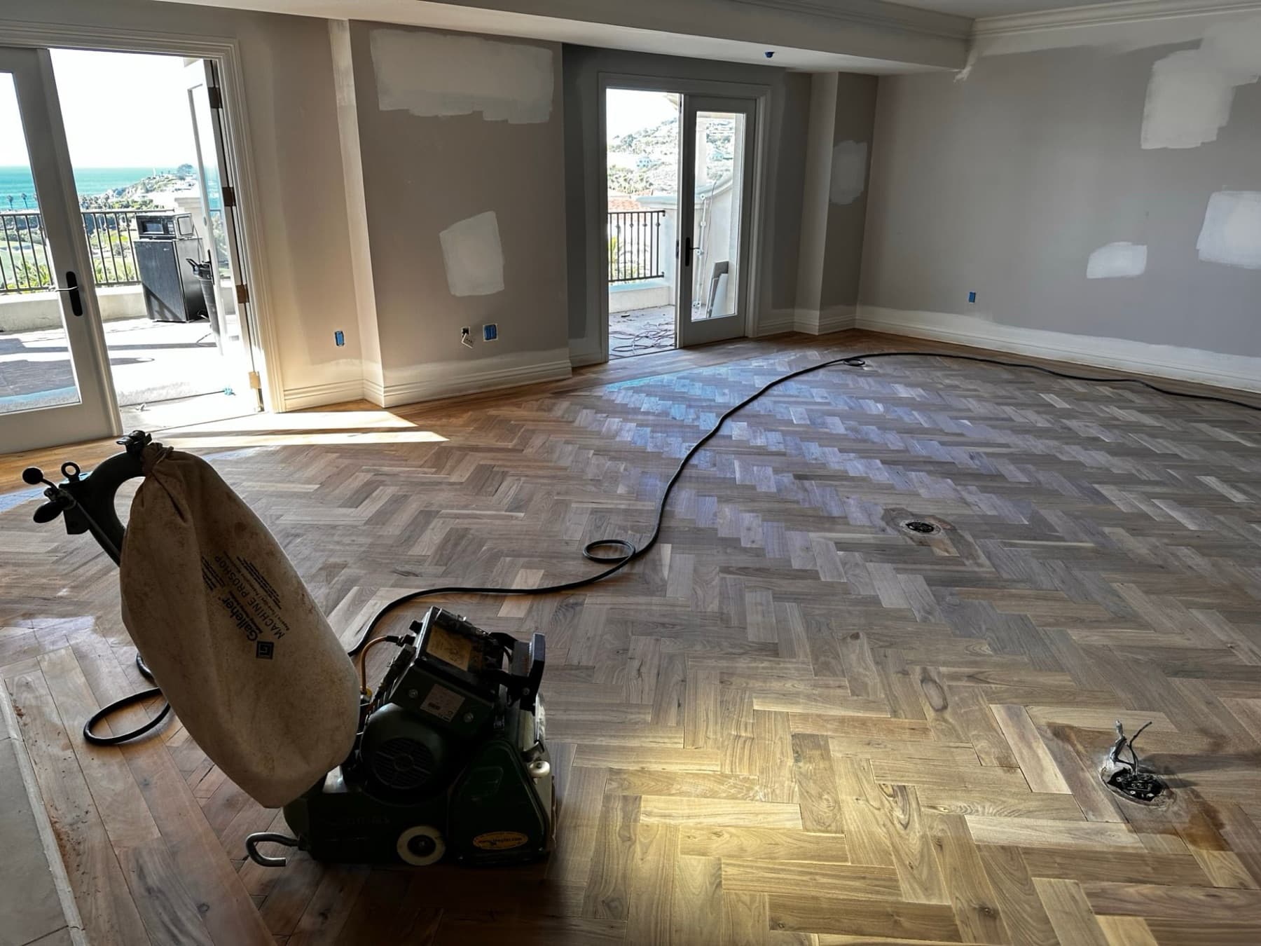 Herringbone floor being sanded, drum sander in the room