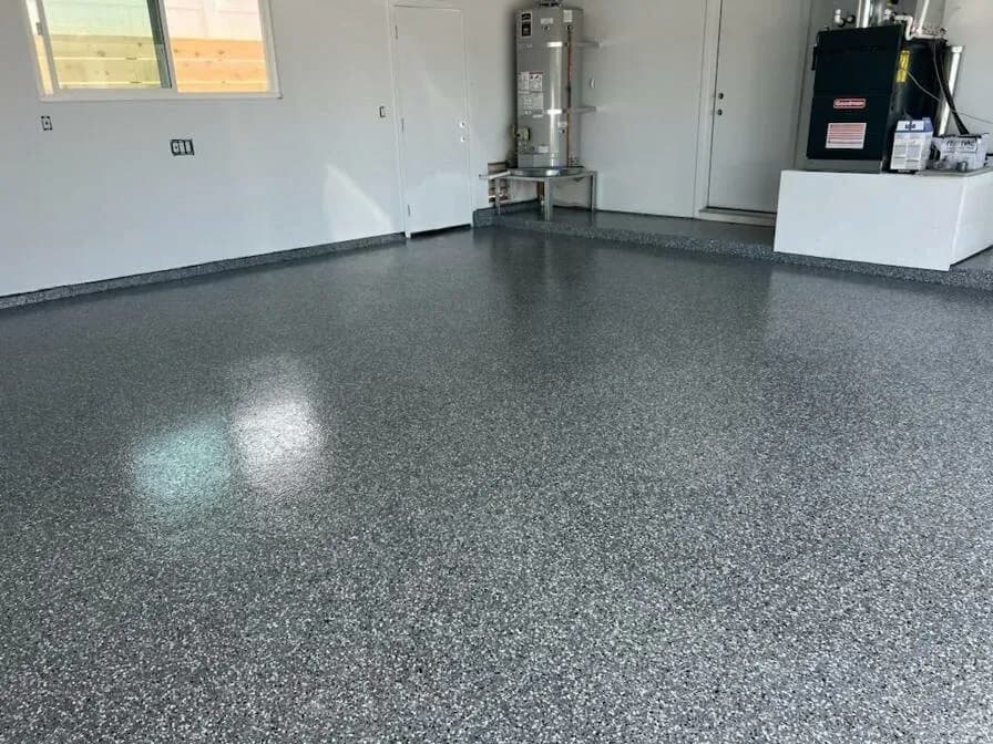 Garage floor finished in gray flake epoxy with a coved edge