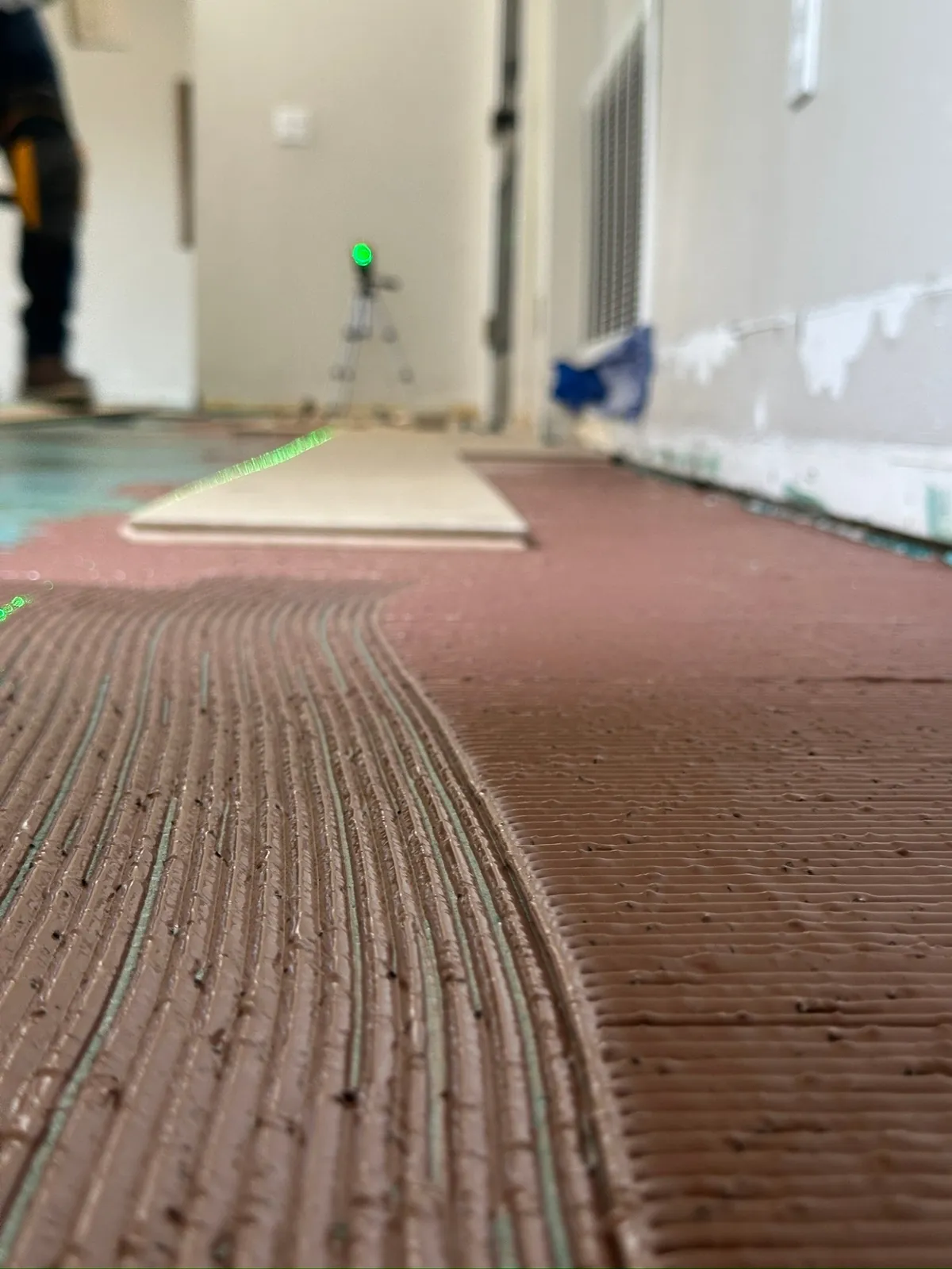 Adhesive troweled on the slab with a laser line set for the first rows