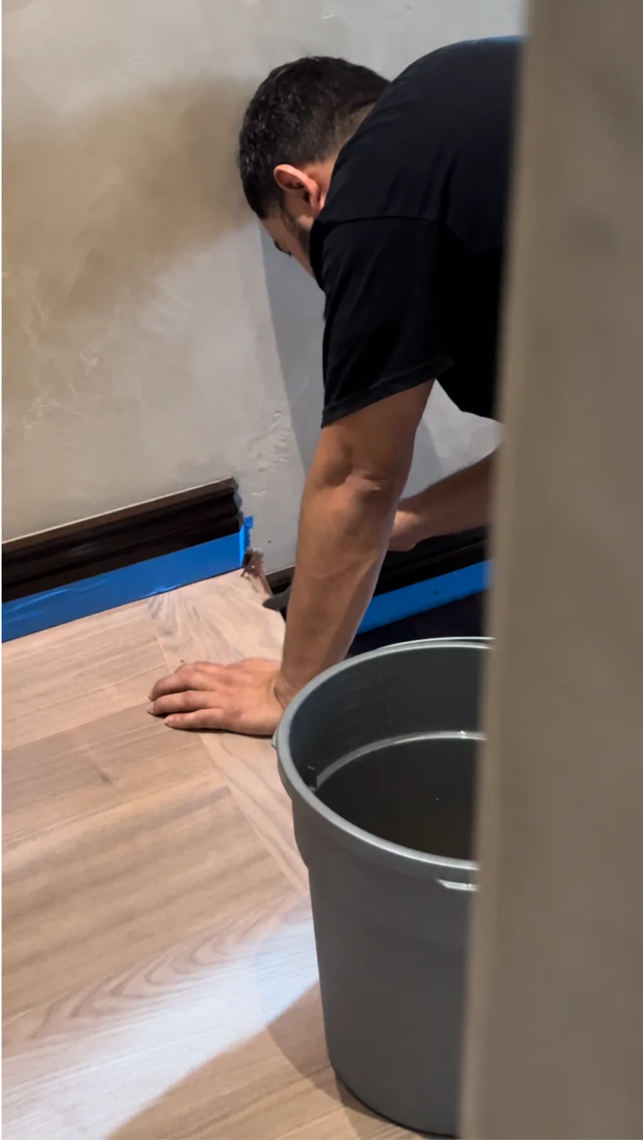Installer pressing a plank into place along the baseboard