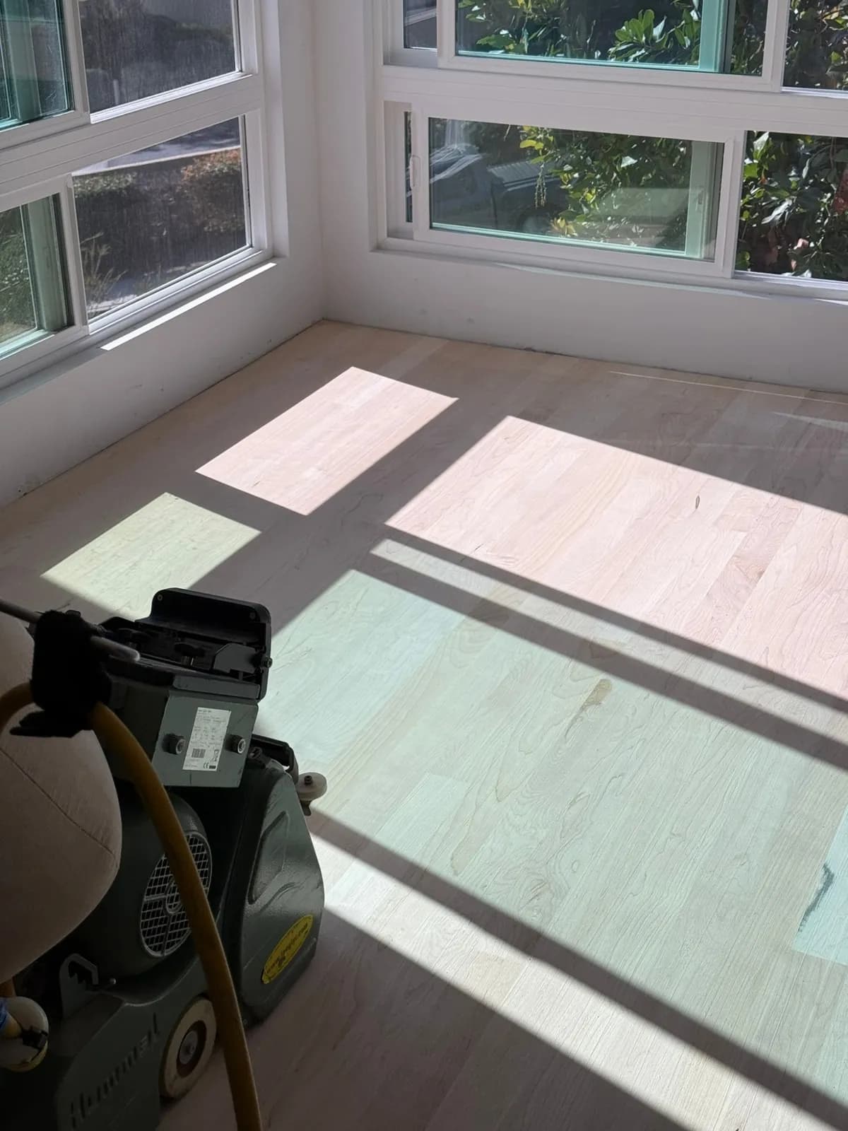 Light floor sanded to bare wood with the sander in the corner