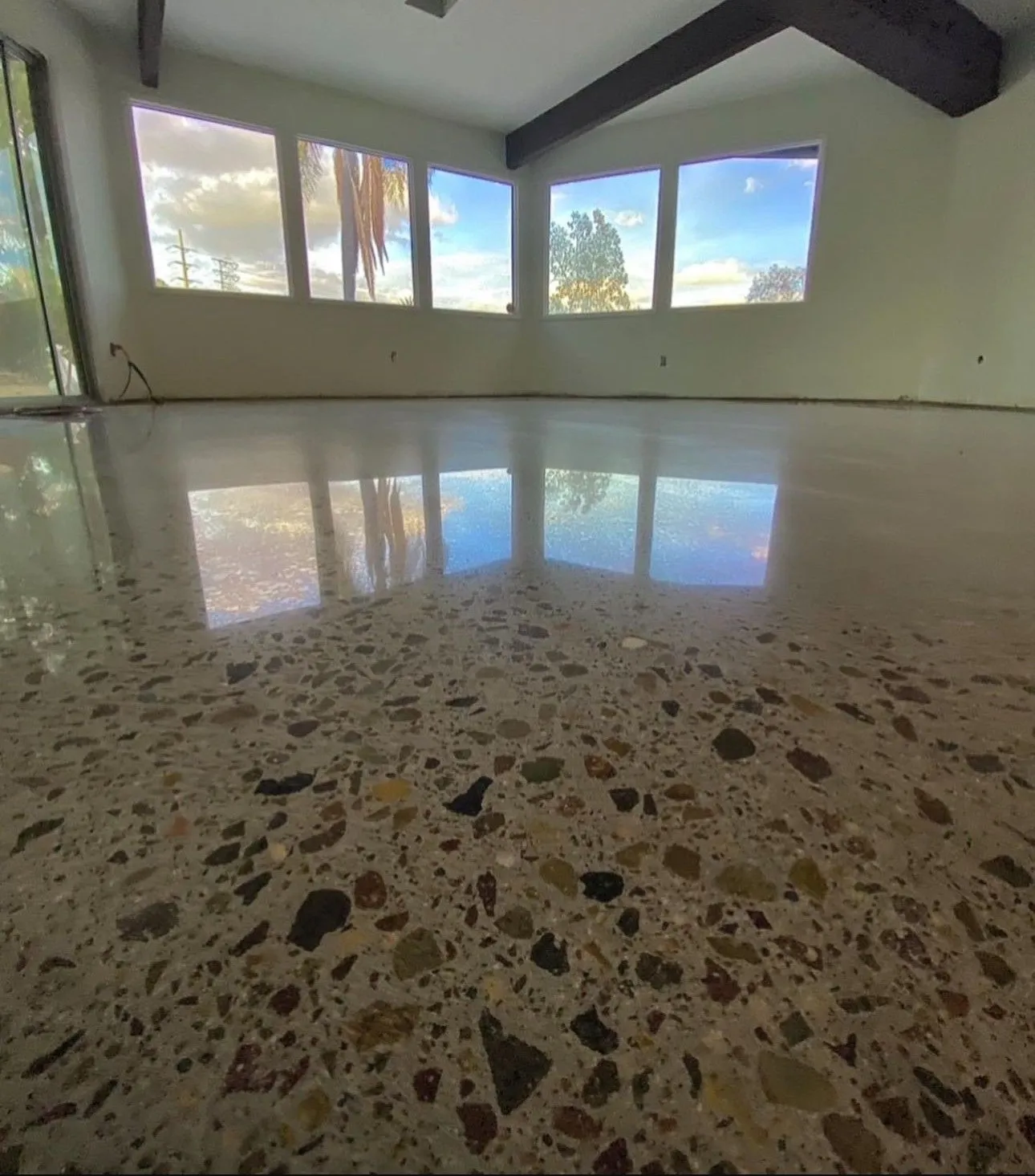 Polished concrete floor with exposed stone, reflecting the windows