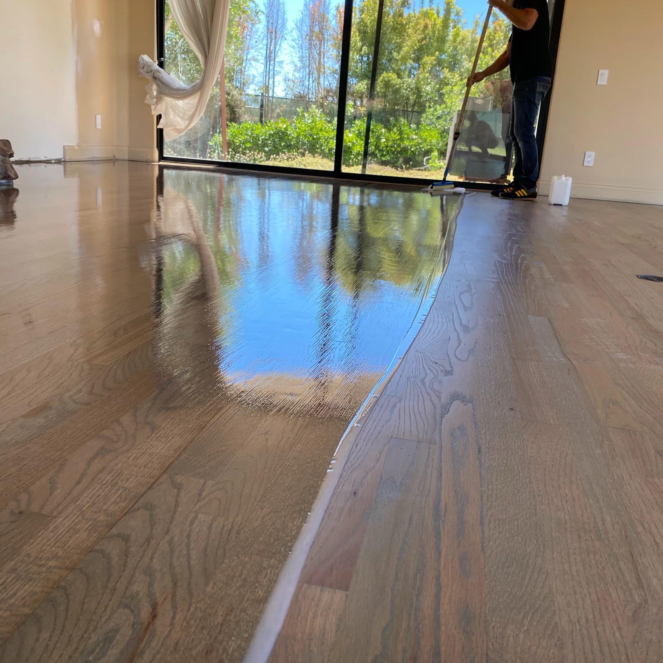 Fresh finish coat being applied to a hardwood floor in San Diego