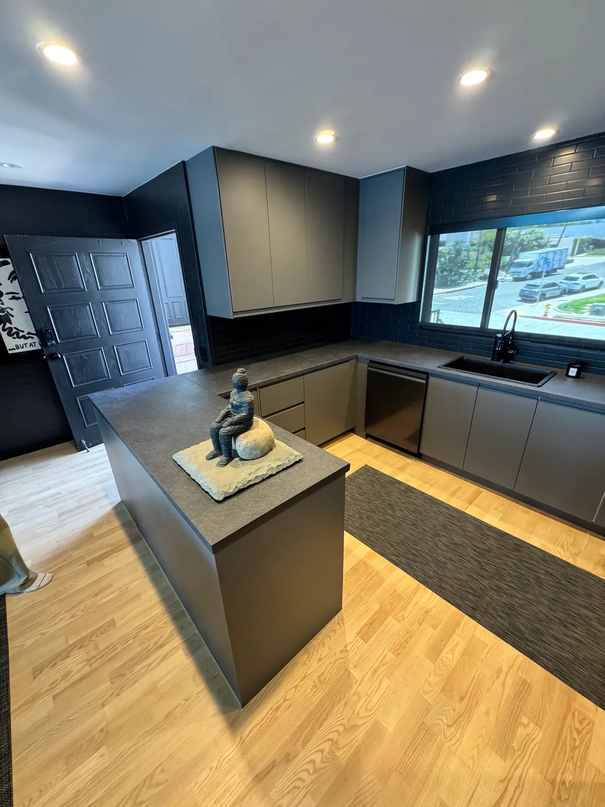 Charcoal kitchen with flat-panel cabinets and a stone-top peninsula, built by Swell
