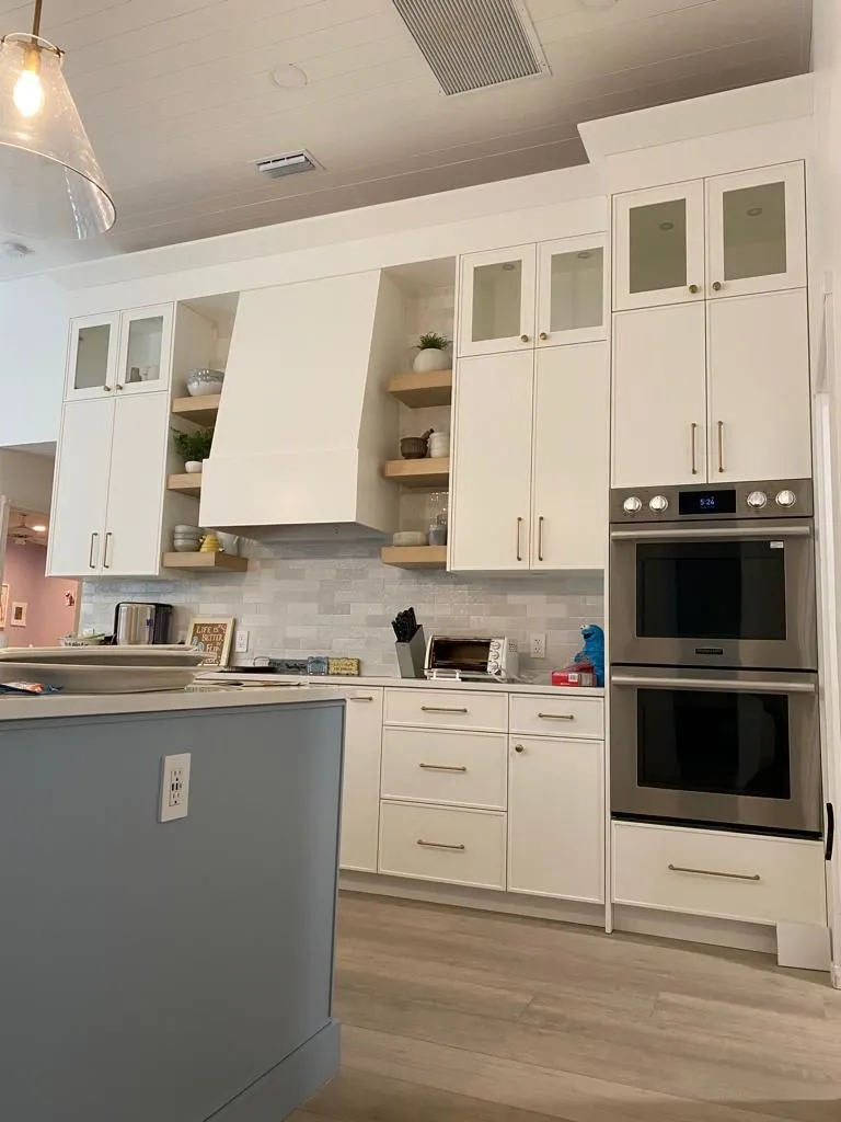 White kitchen with double wall ovens and open shelves