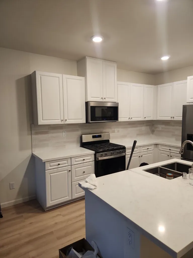White kitchen with a quartz island and gas range