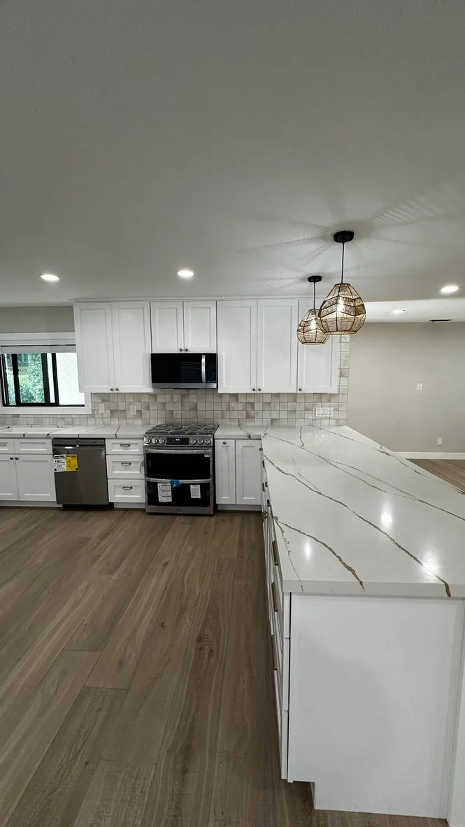White shaker kitchen with marble-look counters and pendant lights