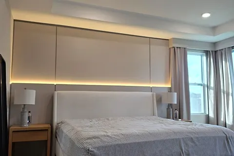 Bedroom wall panels across the full width behind a bed, with a lit line along the base