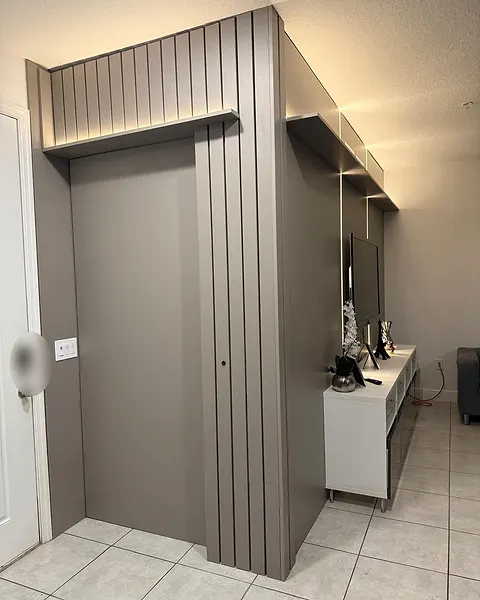 Entry wall in grey with vertical slatted pilasters and a panel