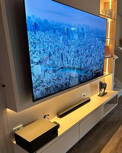 Floating white console under a wall-mounted TV with a warm light under the edge