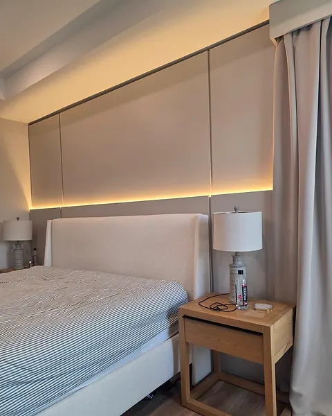 Close view of large wall panels with a lit edge behind a bed