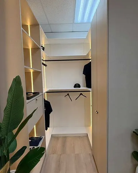 Walk-in closet with lit shelves and hanging rails in a showroom setting