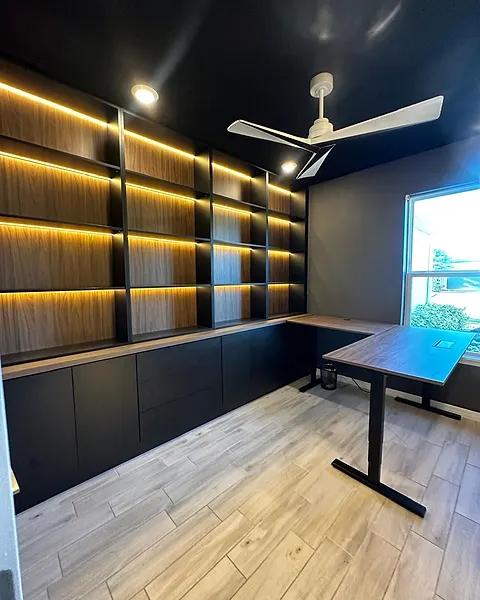 Office wall of open lit shelves above closed dark cabinets