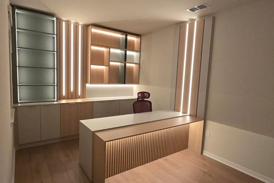 Office with a slatted wall panel, lit shelves and a central desk cabinet