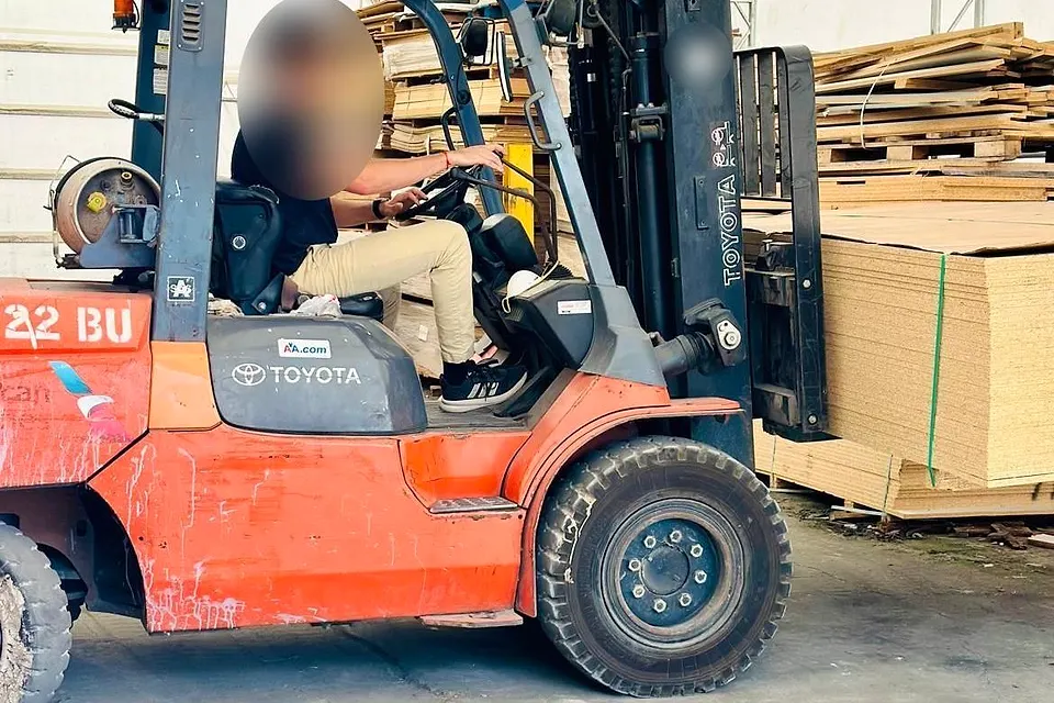 Forklift carrying stacked cabinet board at the workshop