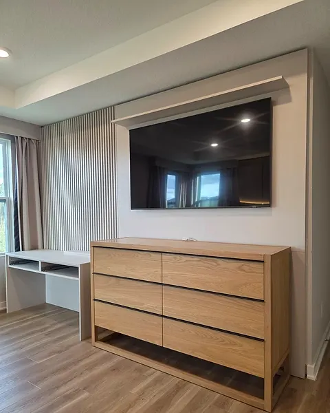 Bedroom wall with fine slats, a wall-mounted TV and a small desk niche