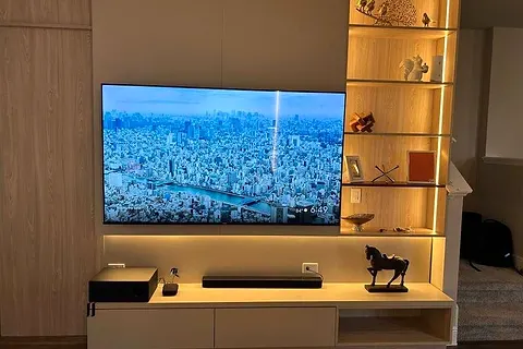 TV wall with lit glass shelves beside the screen and a long low console