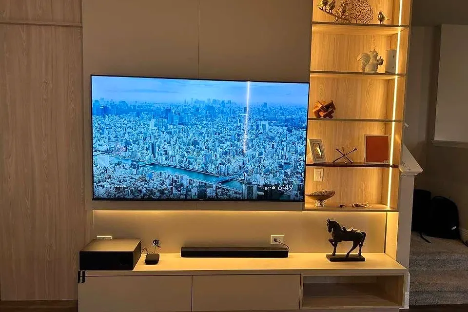 TV wall with lit glass shelves beside the screen and a long low console