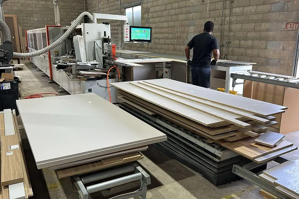 Workshop floor with cut white panels stacked beside machines